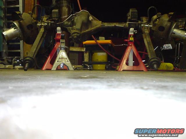 Vehicle rear axle assembly on red jack stands in a garage