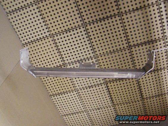 Metal crossmember with bracket attached, mounted against a perforated panel