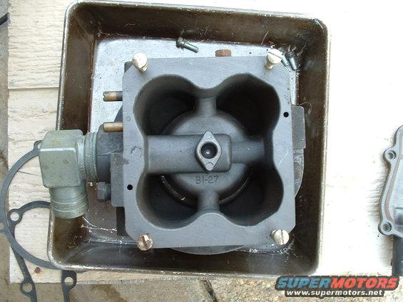 Gray metal carburetor part with BI-27 marking, sitting in a metal tray