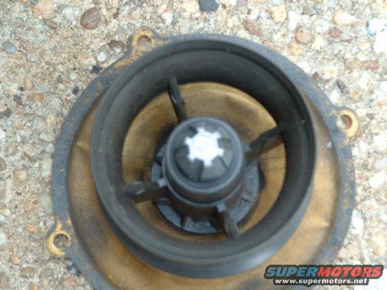 Water pump impeller with brass housing and metal fins, resting on gravel