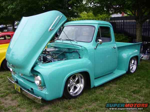 Turquoise 1953 Ford F-100 pickup truck with hood open, chrome wheels, and a yellow license plate