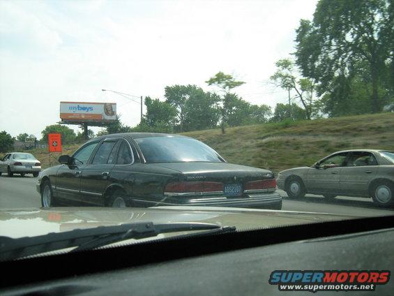 Black sedan with license plate 1052107 on highway, another car to the right