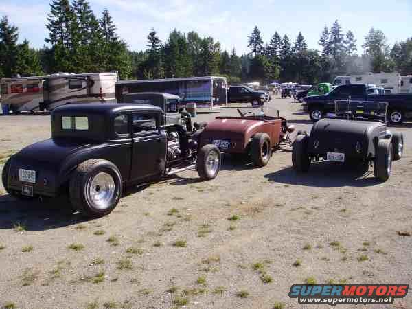 Black hot rod coupe with trailer, rear view. License plate visible