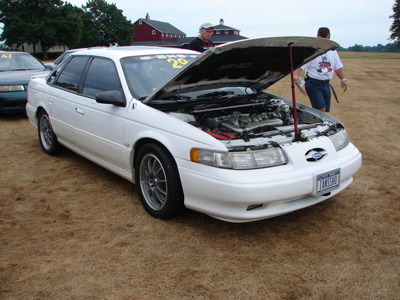 White 1993 Ford Taurus with hood open, showing engine and custom wheels