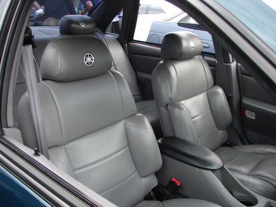 Car interior showing gray leather seats with Yamaha logos on headrests. Other cars visible outside