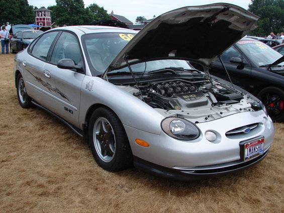 Silver sedan with hood open, showing V8 engine. Black car behind it