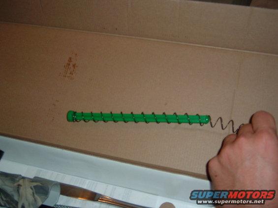 Gun magazine spring with green follower in a cardboard box
