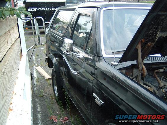 Black Ford Bronco with hood open, side view, showing chrome trim and side mirror