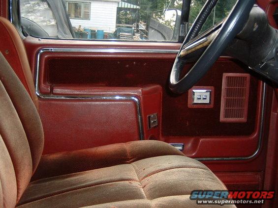 1986 Ford Bronco interior showing red door panel, velour seat, and steering wheel