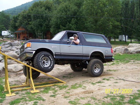 Gray and blue Ford Bronco on a yellow ramp, front wheel elevated