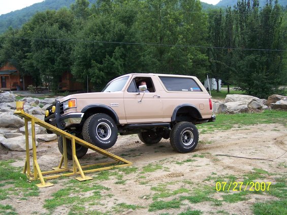 Tan Ford Bronco with off-road tires on a yellow ramp