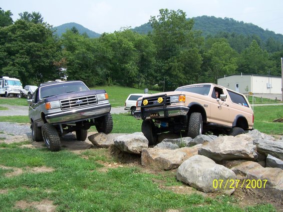 Tan Ford Bronco and purple Ford F-Series truck on rocks. Date stamp '07/27/2007'