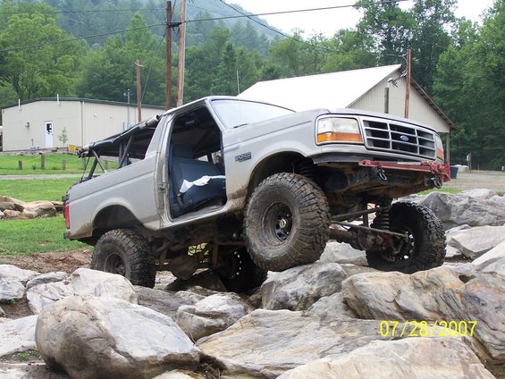 Gray Ford Bronco with lifted suspension and off-road tires navigating rocks