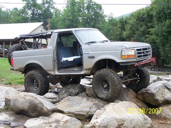 Lifted Bronco on rocks, doors off, spare tire on back