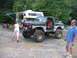 1992 Ford Mustang - A heavily modified pickup truck with large off-road tires is parked next to a recreational vehicle in a gravel lot.