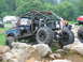 1992 Ford Mustang - This heavily modified off-road vehicle navigates a rocky terrain, with spectators visible in the background.