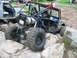 1992 Ford Mustang - A heavily modified off-road vehicle is shown traversing a rocky terrain, with another vehicle partially visible.