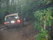 1992 Ford Mustang - A Ford Bronco navigates a challenging, muddy off-road path through a wooded area.