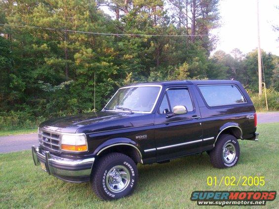 Dark blue 1993 Ford Bronco parked on grass with trees in background