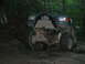 1992 Ford Mustang - This green off-road vehicle, equipped with a front winch, navigates a challenging rocky path through a wooded area.
