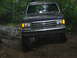 1992 Ford Mustang - A dark blue Ford Bronco navigates a challenging muddy terrain.