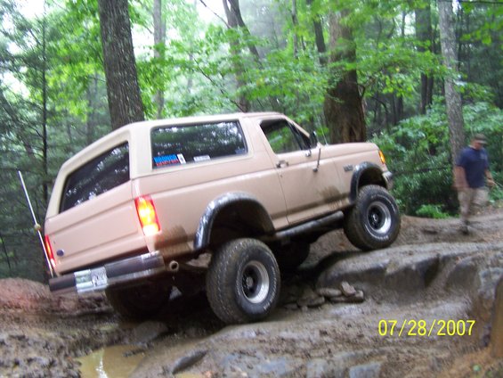 Tan Ford Bronco climbing rocks on a trail