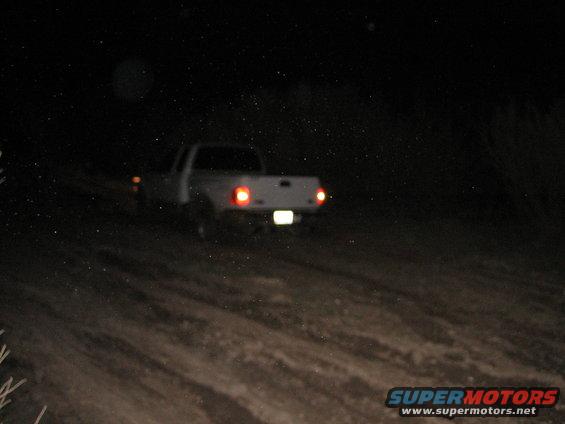 White pickup truck rear view at night on dirt road