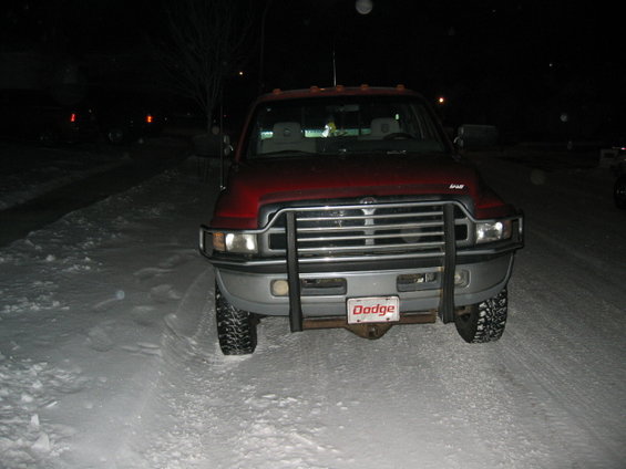 Red Dodge pickup truck with a chrome grille and brush guard, parked in snow