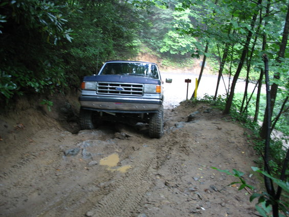Blue Ford F-Series truck navigating a muddy trail