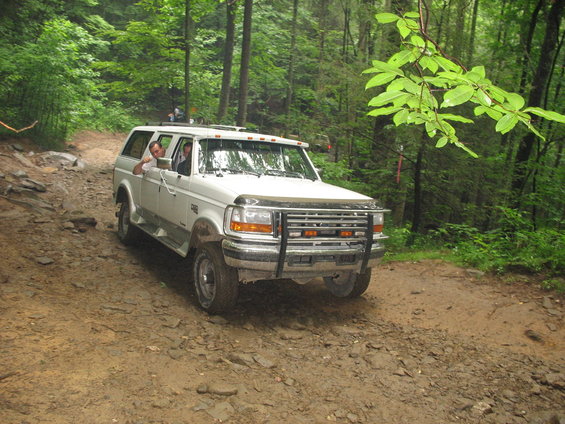 White Ford SUV with a brush guard on a dirt road in a forest