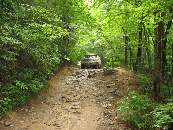 White van on a rocky forest road. Appears to be from the 1990s