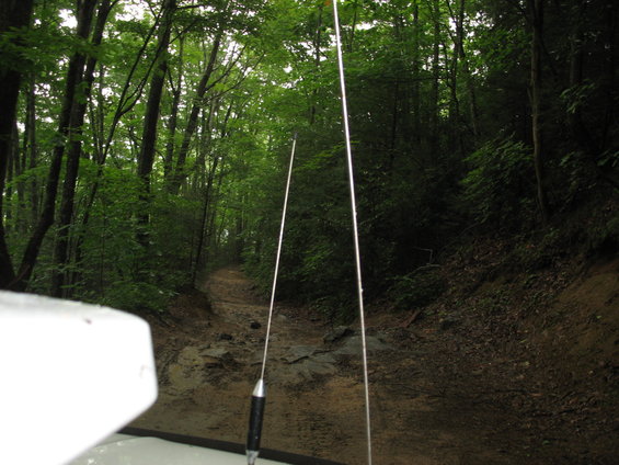 Off-road trail seen from inside a vehicle, with two antennas visible
