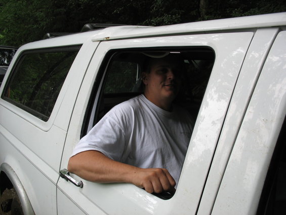 White SUV with a man leaning out the window. The vehicle appears to be from the early to mid-1990s