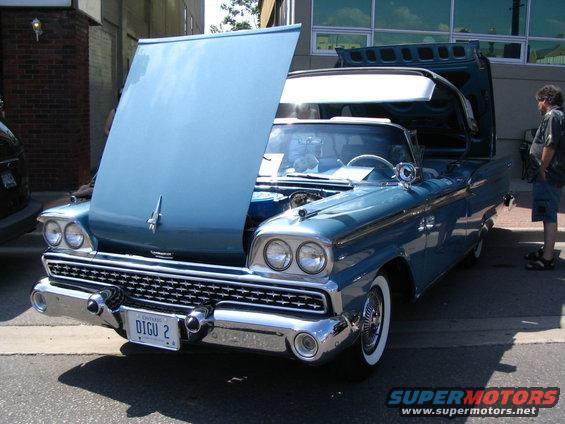 Blue convertible with hood and trunk open, showing engine and interior. Whitewall tires and chrome accents visible