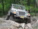2002 Jeep Wrangler - A silver Jeep Wrangler navigates a rocky trail in a wooded area.