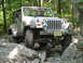 2002 Jeep Wrangler - A silver 2002 Jeep Wrangler navigates a challenging rocky trail, demonstrating its off-road capabilities.