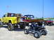 1994 Ford F-250 - Several off-road vehicles, including a modified pickup truck and ATVs, are parked on a sandy beach under a clear blue sky.