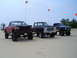 1994 Ford F-250 - Several modified pickup trucks are parked on a sandy terrain, with flags flying in the background.