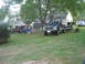1990 Ford Bronco - A dark blue Ford F-Series pickup truck is parked on a lawn with people gathered under a tent in the background.