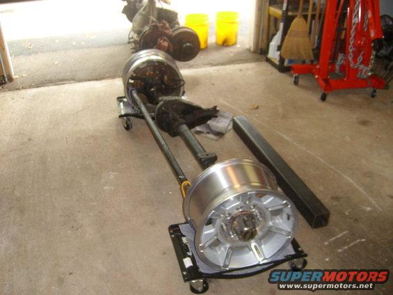 Front axle assembly with large alloy wheels on dollies in a garage