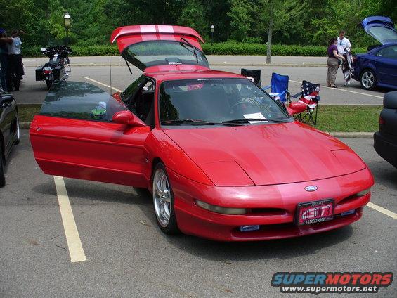 Red 1991 Ford Probe with driver's door and rear hatch open, parked in a lot. Another car and motorcycle are visible