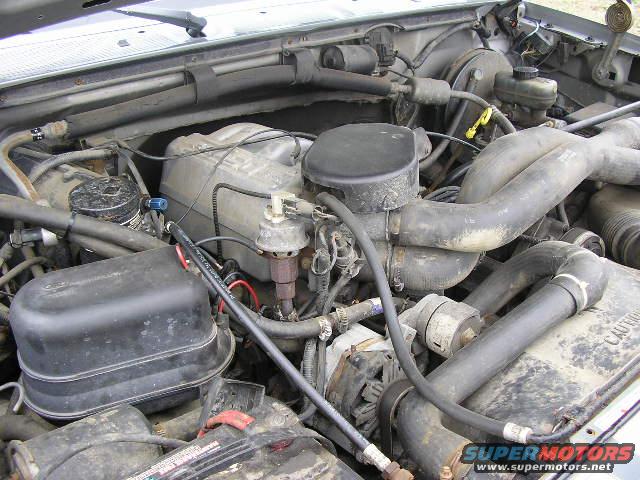 engine bay with hoses, air filter housing, and brake fluid reservoir