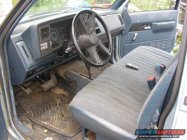 Interior of a light blue truck showing the dashboard, steering wheel, and seat