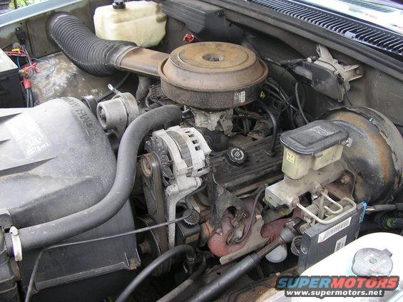 Engine bay with V8 engine, alternator, air filter housing, and brake fluid reservoir
