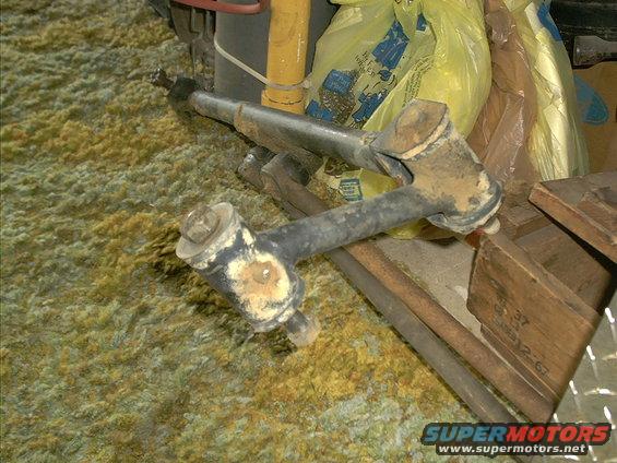 Rusty suspension component with bolts, resting on carpeted floor
