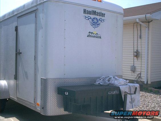 Rear view of a white enclosed cargo trailer with a black toolbox mounted on the tongue