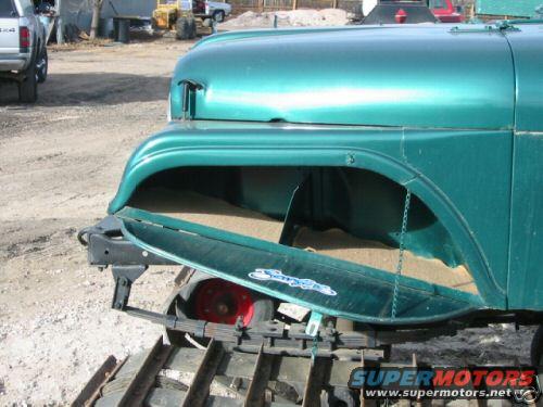 Green jeep with tracks and open storage compartment filled with sand. Supermotors.net logo visible