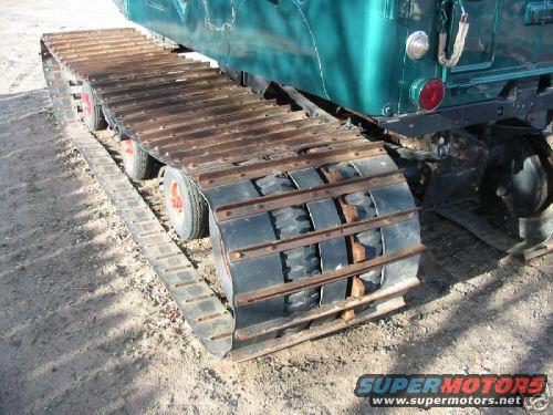 Close-up of a green tracked vehicle's rubber and metal treads