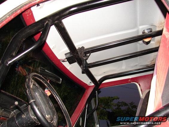 Interior view of a vehicle with a black roll cage and red trim around the windows. Steering wheel visible
