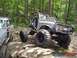1992 Ford Mustang - Two off-road vehicles navigate a rocky trail in a wooded area.
